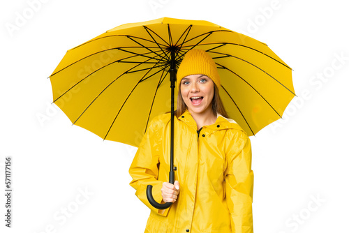 Young blonde woman with rainproof coat and umbrella over isolated chroma key background with surprise facial expression