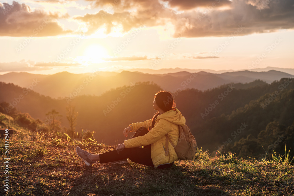 Happy young woman traveler relaxing and looking at the beautiful sunrise on the top of mountains, Travel lifestyle concept