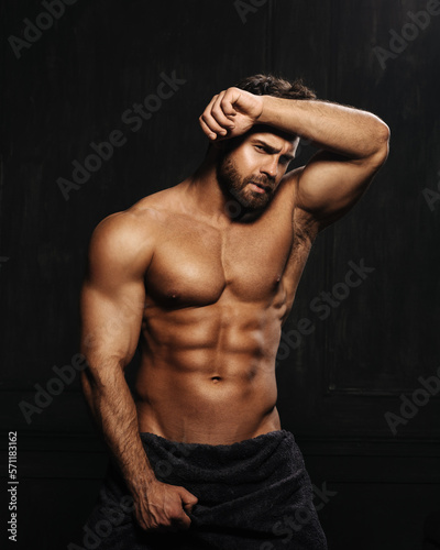 фотография Brutal sexy man with six pack abs in towel at black background