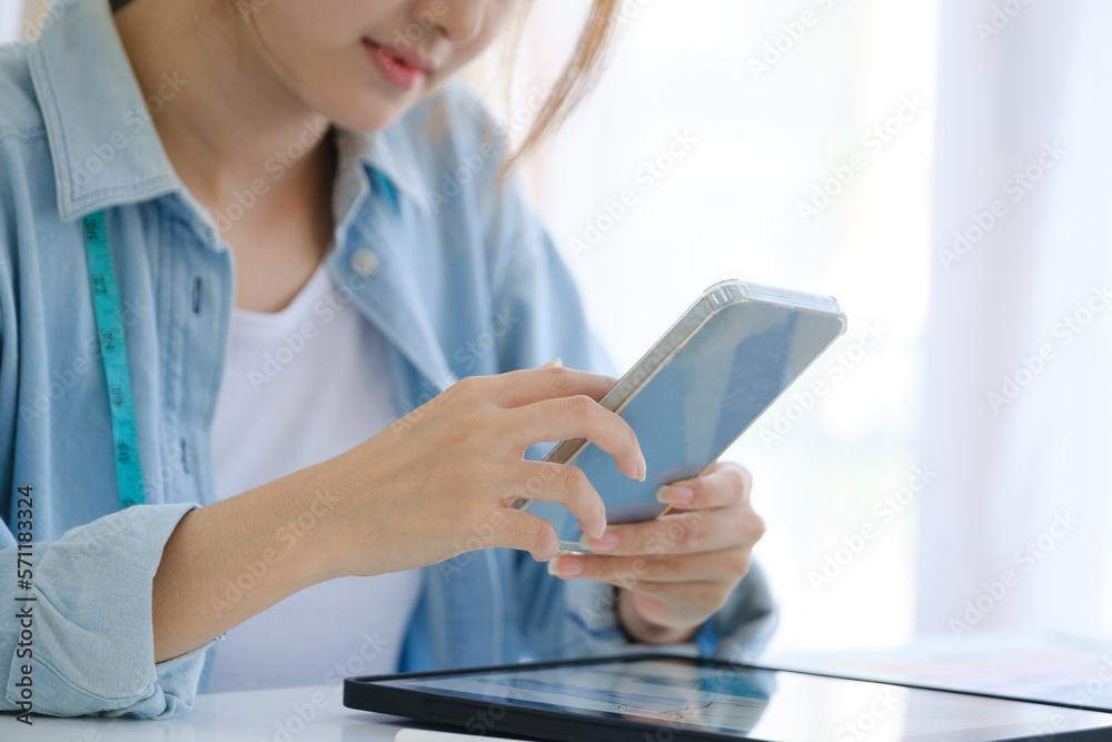 Close up of young asian fashion designer. She is using a mobile phone in contact with her customers. Close up of young asian fashion designer. She is using a mobile phone in contact with her customers.