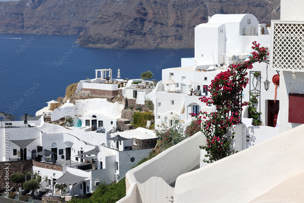 Fototapeta premium Whitewashed houses with terraces and pools and a beautiful view in Oia on Santorini island, Greece