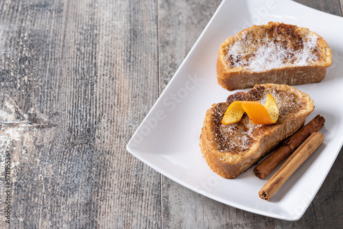 Traditional homemade Spanish torrijas decorated with cinnamon and orange peel on wooden table photo