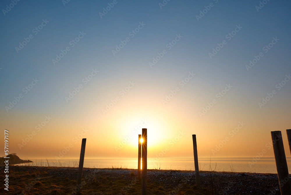 Amazing sunset on the beach, orange and blue colors, bright light coming through the posts Amazing sunset on the beach, orange and blue colors, bright light coming through the posts