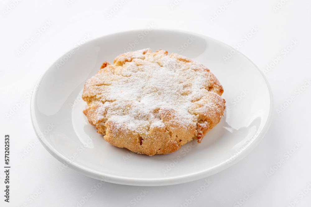 One freshly baked cookie with powdered sugar on a white plate on the table. Homemade cakes for breakfast. One freshly baked cookie with powdered sugar on a white plate on the table. Homemade cakes for breakfast.
