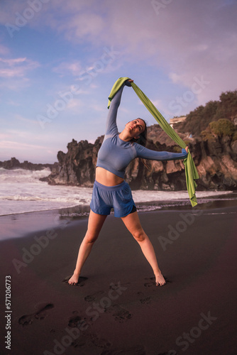 sporty woman stretching her shoulders on the beach.