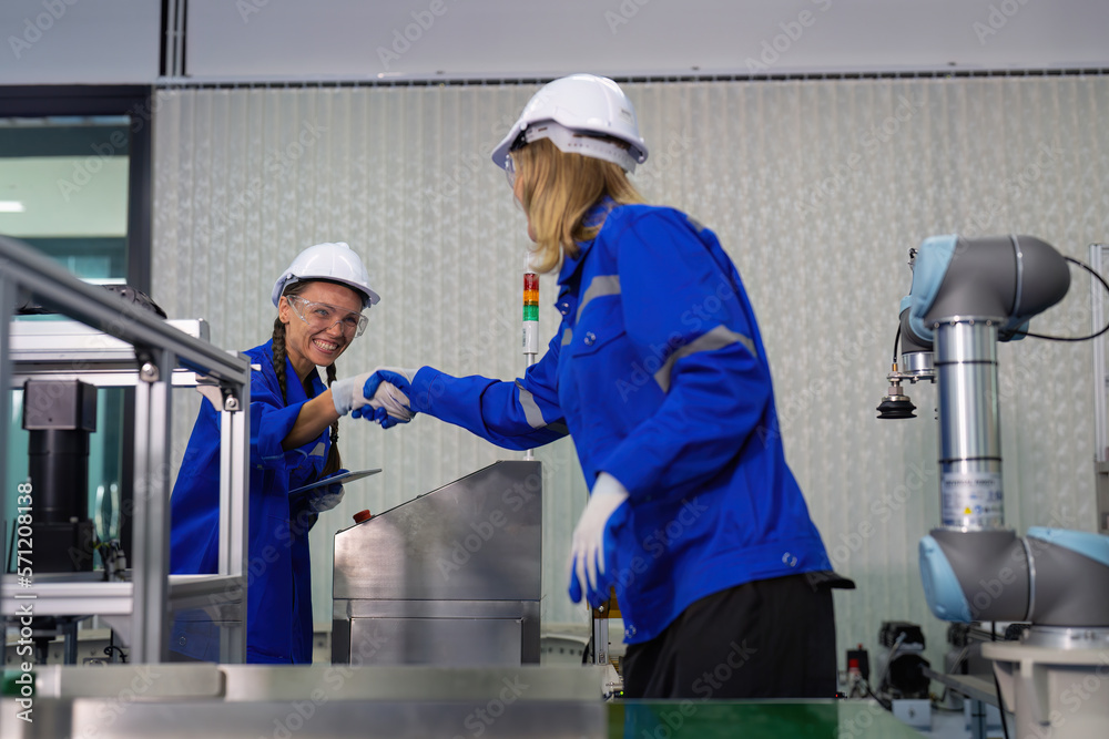 Automation girls engineer in factory testing logistic robot arm picking boxes from conveyor Automation girls engineer in factory testing logistic robot arm picking boxes from conveyor