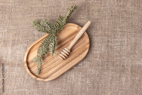 Honey spoon on wooden tray. Burlap background. Natural fabric