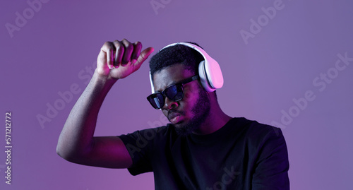 Young African American man in sunglasses and headphones listens to music and dances. © KDdesignphoto