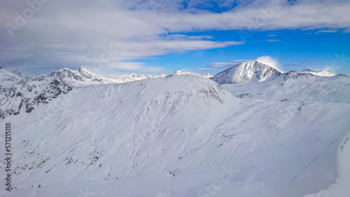 Panoramic view of austrian alps in Winter. High peaks covered with snow and clouds on a sunny winter day. © Lukas