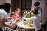 Children eat fruits and desserts, drink tea at home in the evening kitchen.