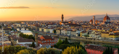The Florence cityscape with the Ponte Vecchio over Arno river, the Palazzo Vecchio and the Florence Cathedral in an orange sunset.