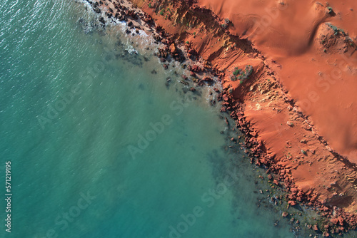 Cape Peron view from the sky. Aerial picture of orange land next to the ocean. Location Shark Bay, Western Australia. Top down with a drone. Orange rocks and blue water.