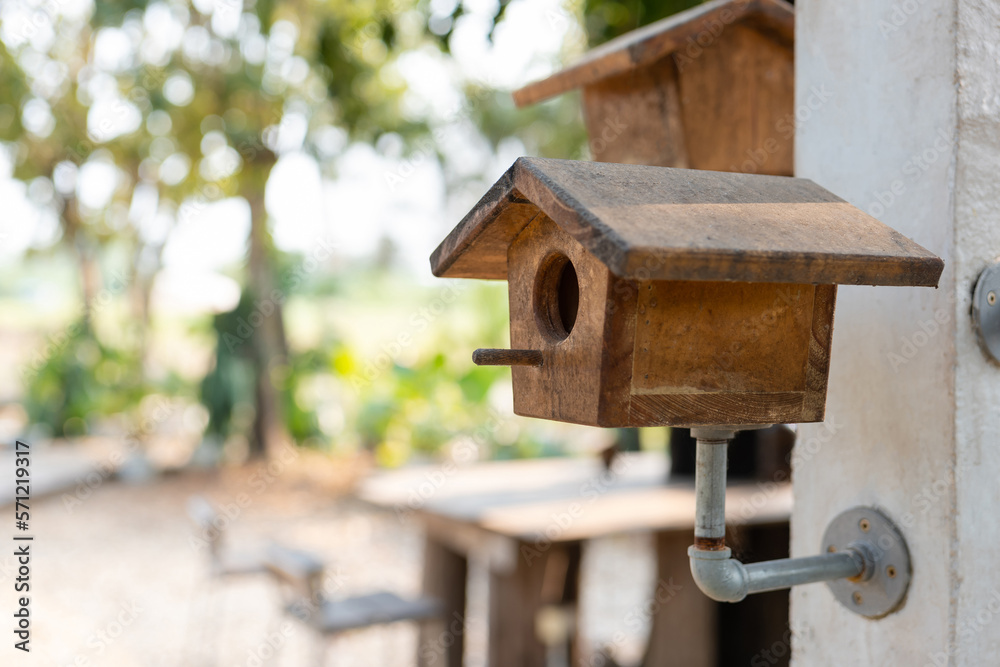 Old wooden bird houses set up on the metal pipe and concrete pole in the garden