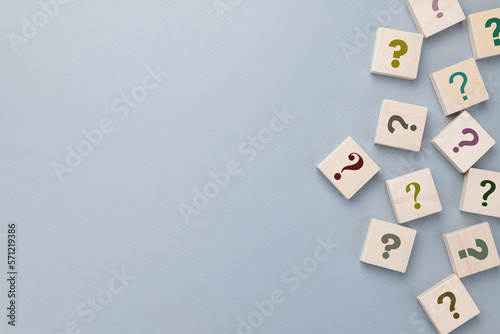 Many question mark signs on wood blocks on gray paper background with copy space