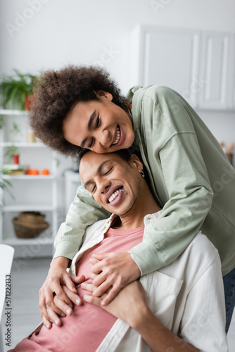 Happy african american woman holding hands of boyfriend at home.