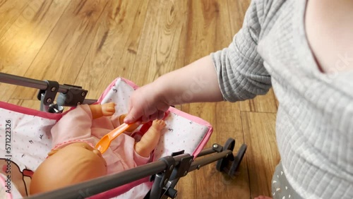 A young girl feeding her baby doll in a living room