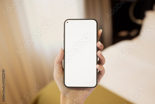 CU 20s Caucasian female holding a phone in a left hand, hotel room bed in bg