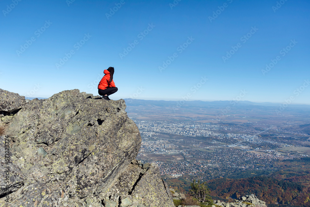 Woman sitting on a rocks high  in the autumn  mountain above the city of Sofia. Vitosha mountain,  ,Bulgaria