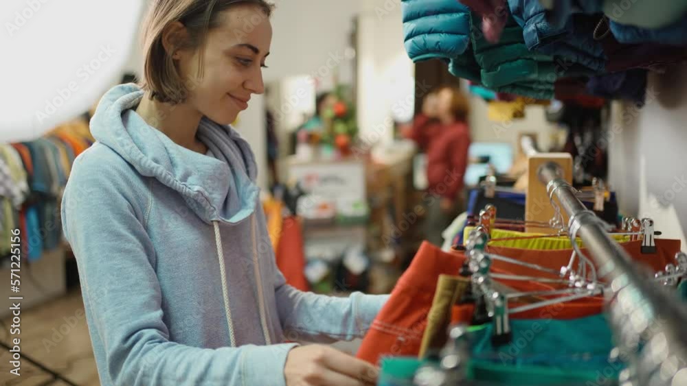 attractive woman in outdoor clothing store. woman chooses pants in store, sale, new collection, girl looking and buys clothing for herself for sports and activity attractive woman in outdoor clothing store. woman chooses pants in store, sale, new collection, girl looking and buys clothing for herself for sports and activity