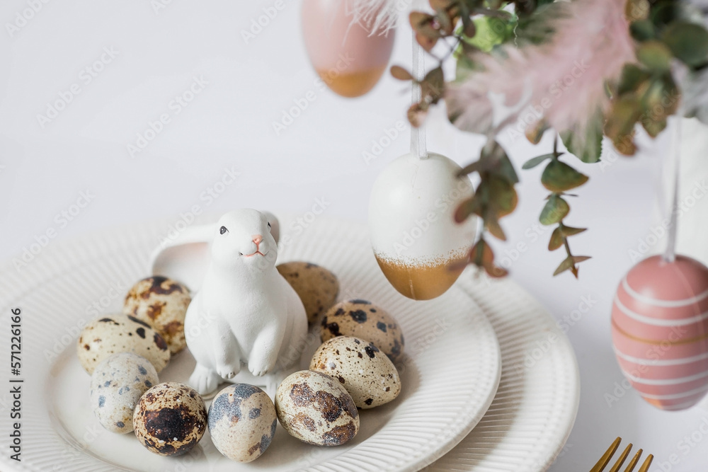 Banner. The concept of a bright Easter holiday. A bouquet of flowers with feathers, white rabbits and Easter eggs in a plate on a white isolated background. Beautiful Easter card. Banner. The concept of a bright Easter holiday. A bouquet of flowers with feathers, white rabbits and Easter eggs in a plate on a white isolated background. Beautiful Easter card.