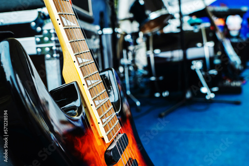 A fragment of an electric guitar against the backdrop of a concert venue. Preparation for a musical performance or rehearsal of a musical group. Foreground
