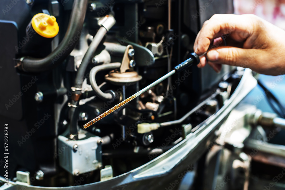 Checking the oil level in the boat engine. A dipstick with marks and an