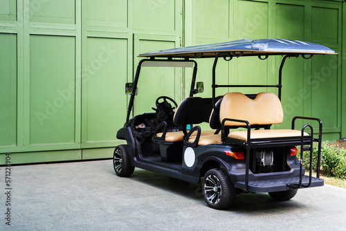 Compact electric car for transporting guests and visitors in a park or public place. A parked electric car in front of a green building. Close-up photo