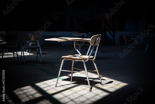 A single school desk in a dark abandoned classroom