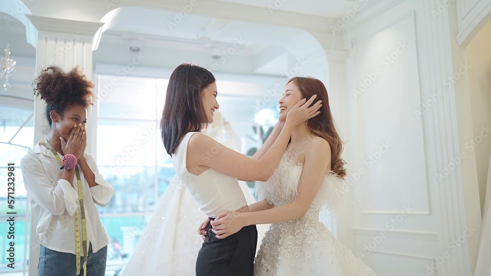 Naklejka premium Asian beautiful bridesmaids congratulate your friend on becoming a bride chossing the white wedding dress for wedding ceremony at wedding studio