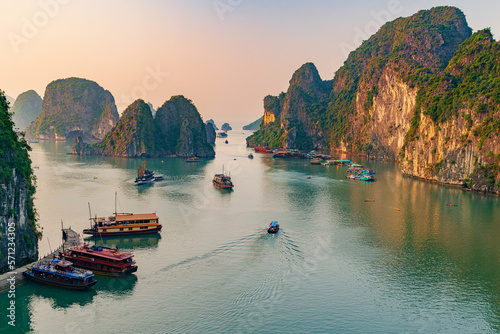 Sunset over the halong bay, Boats in a body of water with mountains in the background, Boats in a body of water with a large cliff, Boats in a body of water