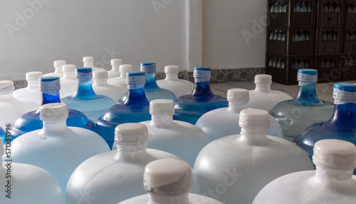 Plastic big bottles or white and blue gallons of purified drinking water inside the production line. Water drink factory
