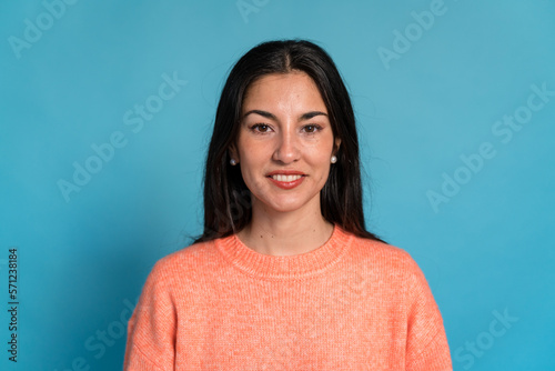 Smiling woman in sweater looking at camera against blue background