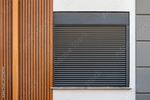 The building whose facade is covered with wooden patterned PVC panels and whose window is made of shutters photo