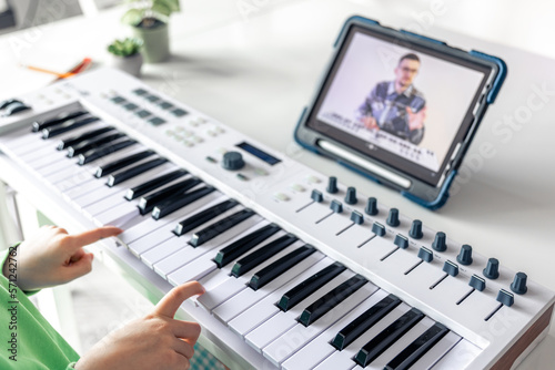 Little girl learns to play the piano with online, distance learning music. photo