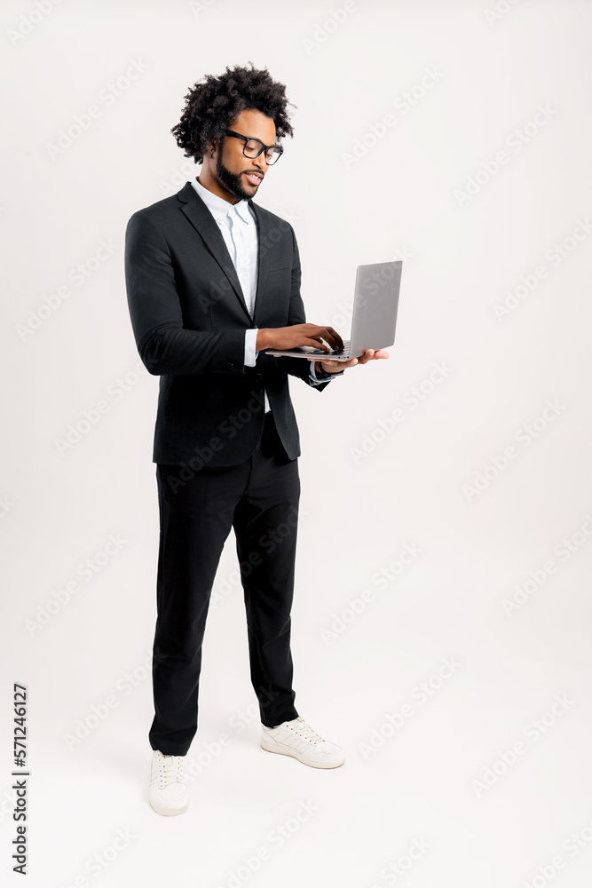 Smiling well dressed African American modern male entrepreneur manager or business owner in smart casual black suit using laptop standing isolated on white full length Stock Photo Adobe Stock