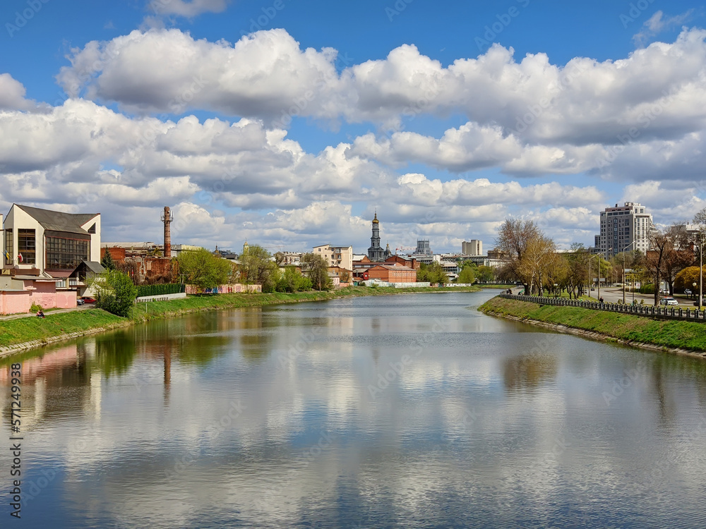 Cityscape Kharkiv city and Lopan river embankment on a sunny spring day. Cumulus clouds on blue sky