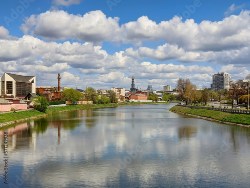 Cityscape Kharkiv city and Lopan river embankment on a sunny spring day. Cumulus clouds on blue sky