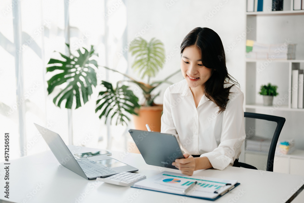 Young beautiful woman using laptop and tablet while sitting at her working place. Concentrated at work.. Young beautiful woman using laptop and tablet while sitting at her working place. Concentrated at work..