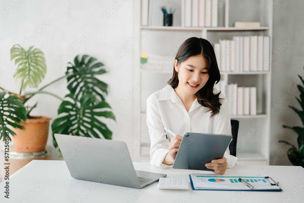Young beautiful woman using laptop and tablet while sitting at her working place. Concentrated at work.. Young beautiful woman using laptop and tablet while sitting at her working place. Concentrated at work..
