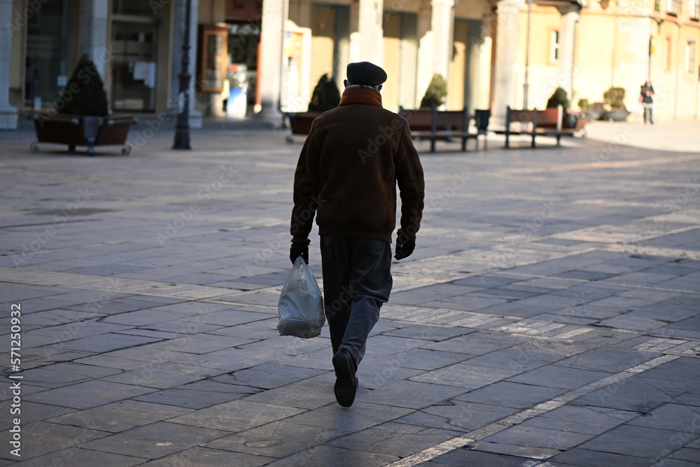 An elderly man carries his groceries home in Leon-Spain.