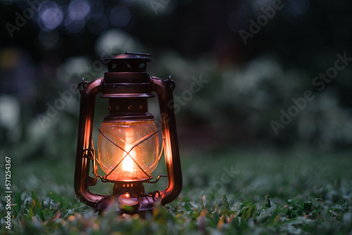 lantern in the garden, antique oil lamp On the grass in the forest in the evening camping atmosphere.Travel Outdoor Concept image © Pongvit