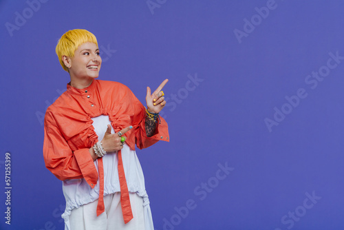 Young beautiful stylish short-haired smiling woman pointing and looking aside