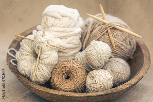 Wooden bowl with threads for knitting yarns close-up.