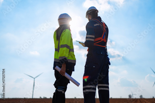 Wind turbine service engineer standing on ground planning for maintenance electricity generator