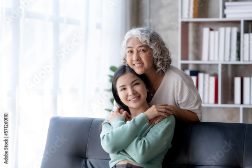 Beautiful Asian woman is taking care of her mother at home in the living room, sitting and resting, having a happy and warm conversation as a mother and daughter.