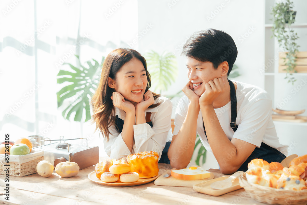Young Asian couple doing holiday together in the kitchen happily wearing apron. love and valentine concept Young Asian couple doing holiday together in the kitchen happily wearing apron. love and valentine concept
