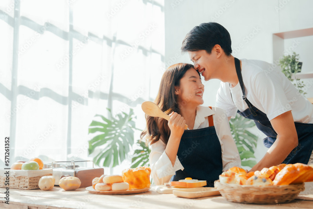 Young Asian couple doing holiday together in the kitchen happily wearing apron. love and valentine concept Young Asian couple doing holiday together in the kitchen happily wearing apron. love and valentine concept