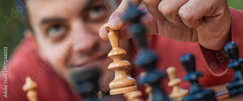 Hand of a man taking a chess piece to make the next move in a chess game. Close up. Spring day outside.