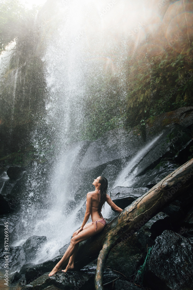 Obraz premium Gorgeous wet woman posing beside mighty Phnom Kulen waterfall