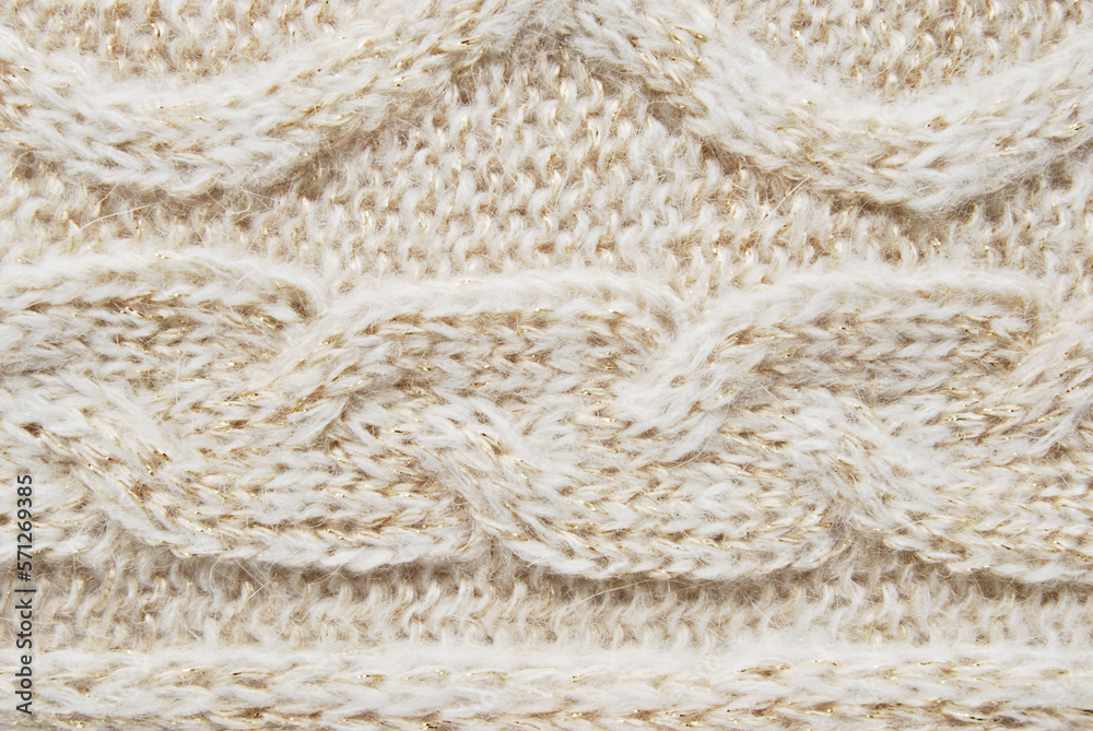 Beige soft woolen sweater surface with cable ornament texture and golden metallic fibres as background